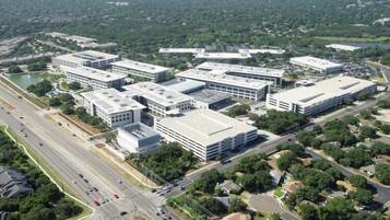 An aerial view of a commercial complex with multiple buildings, roads, and greenery.