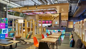A modern hotel lobby with seating areas, a reception desk, and a colorful digital display. - Aloft by Marriott Austin Northwest (Austin)