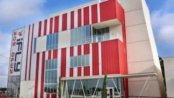 A modern building with a red and white facade, large windows, and a prominent entrance.