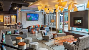 A modern lounge area with a large TV, comfortable seating, and a fireplace. - Aloft by Marriott Austin Northwest (Austin)