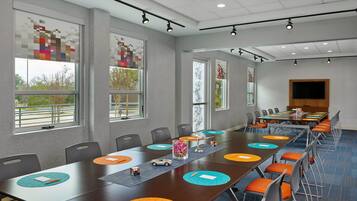 A conference room with a long table, chairs, and a television screen.