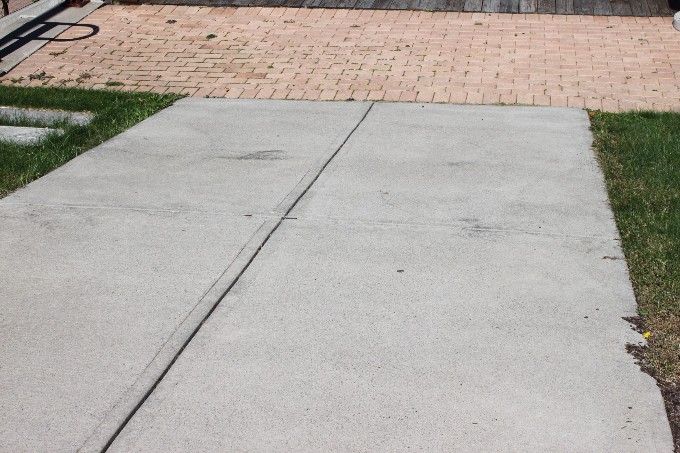 A concrete pathway leading to a brick-paved area.
