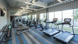 Une salle de sport équipée de tapis de course, de vélos elliptiques et de matériel de musculation.