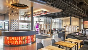 Un intérieur moderne avec un espace de détente circulaire central, de nombreuses tables et un élément décoratif mural distinctif, mis en valeur par un éclairage particulier.