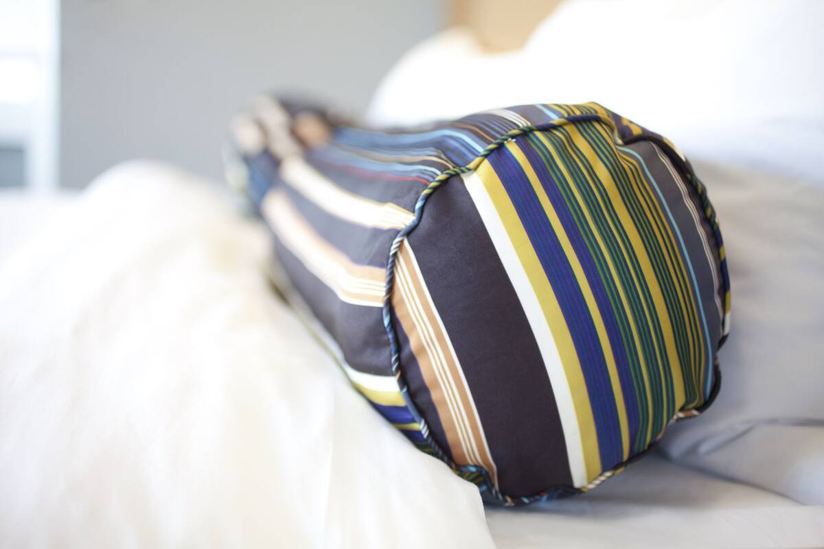 A bed with striped pillows and a white blanket.