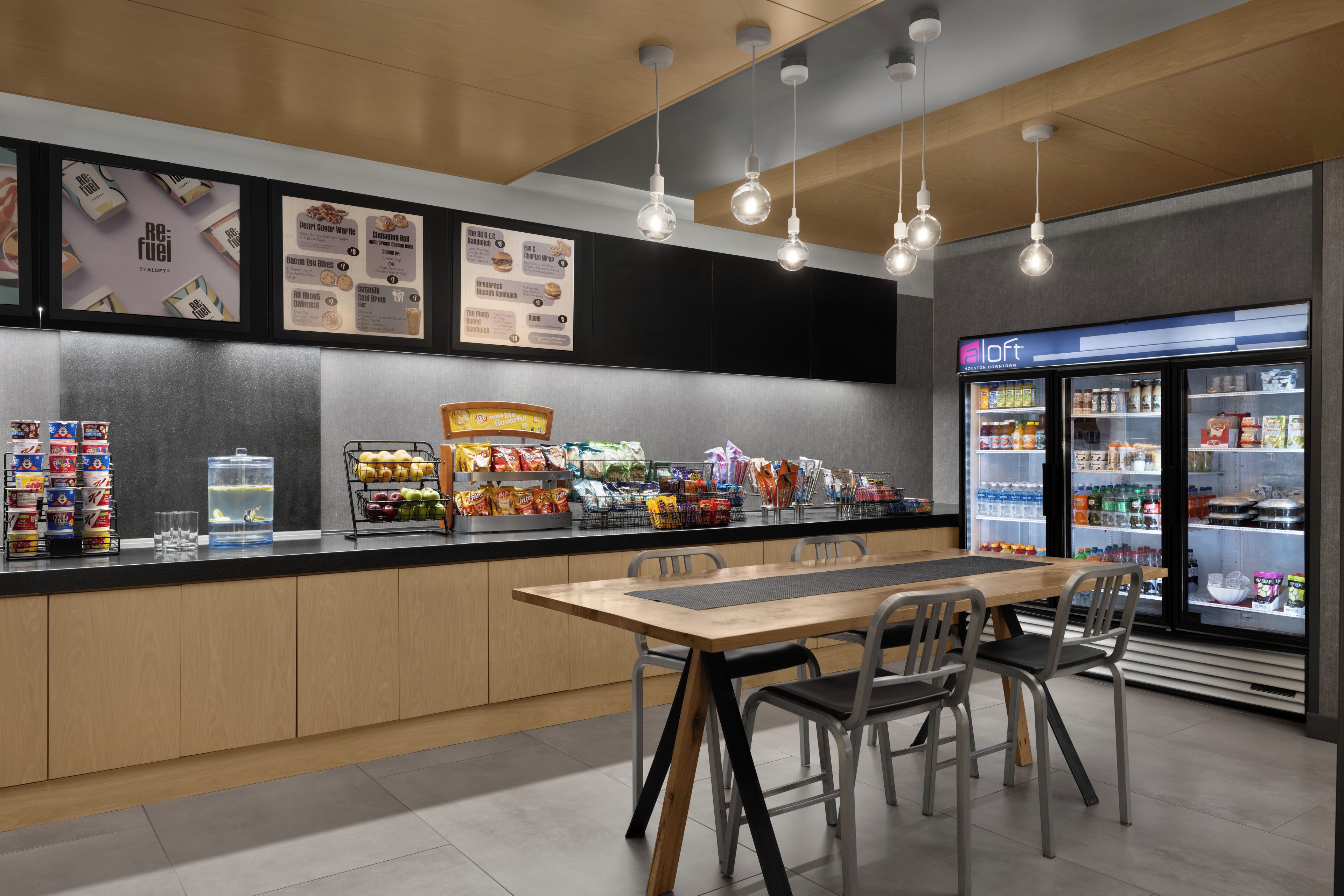 A cafe with a counter, menu boards, seating area, and a refrigerated display.