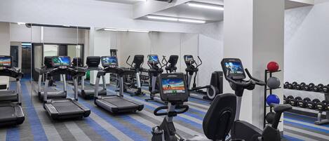 A gym with treadmills, elliptical machines, and weightlifting equipment.