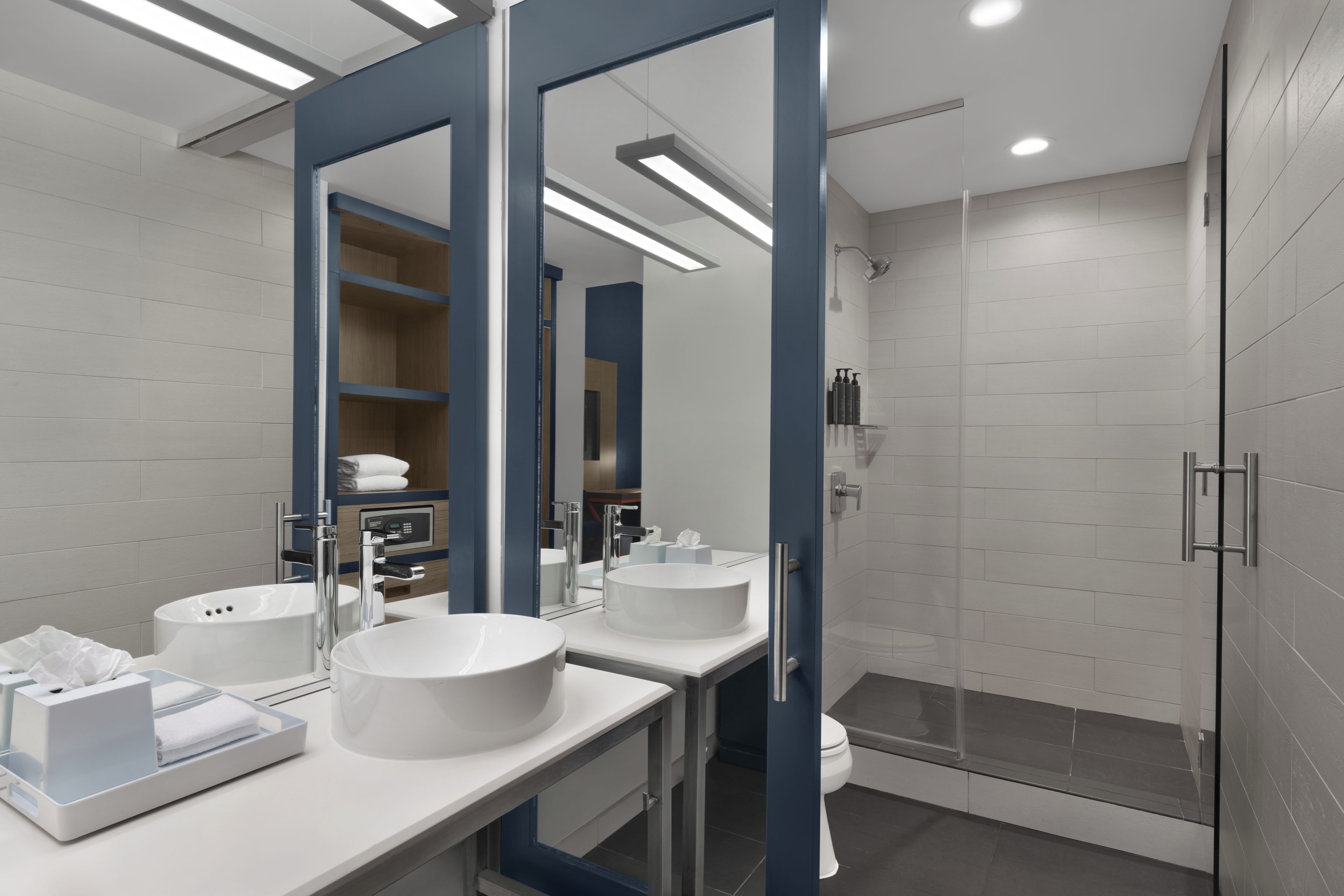 Un baño moderno con dos lavamanos, una ducha y zona de ducha con mampara de vidrio.