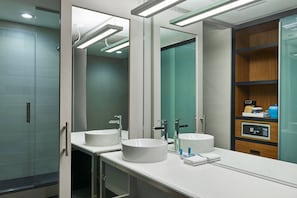 A modern bathroom with two sinks, a mirror, and a vanity with a control panel.