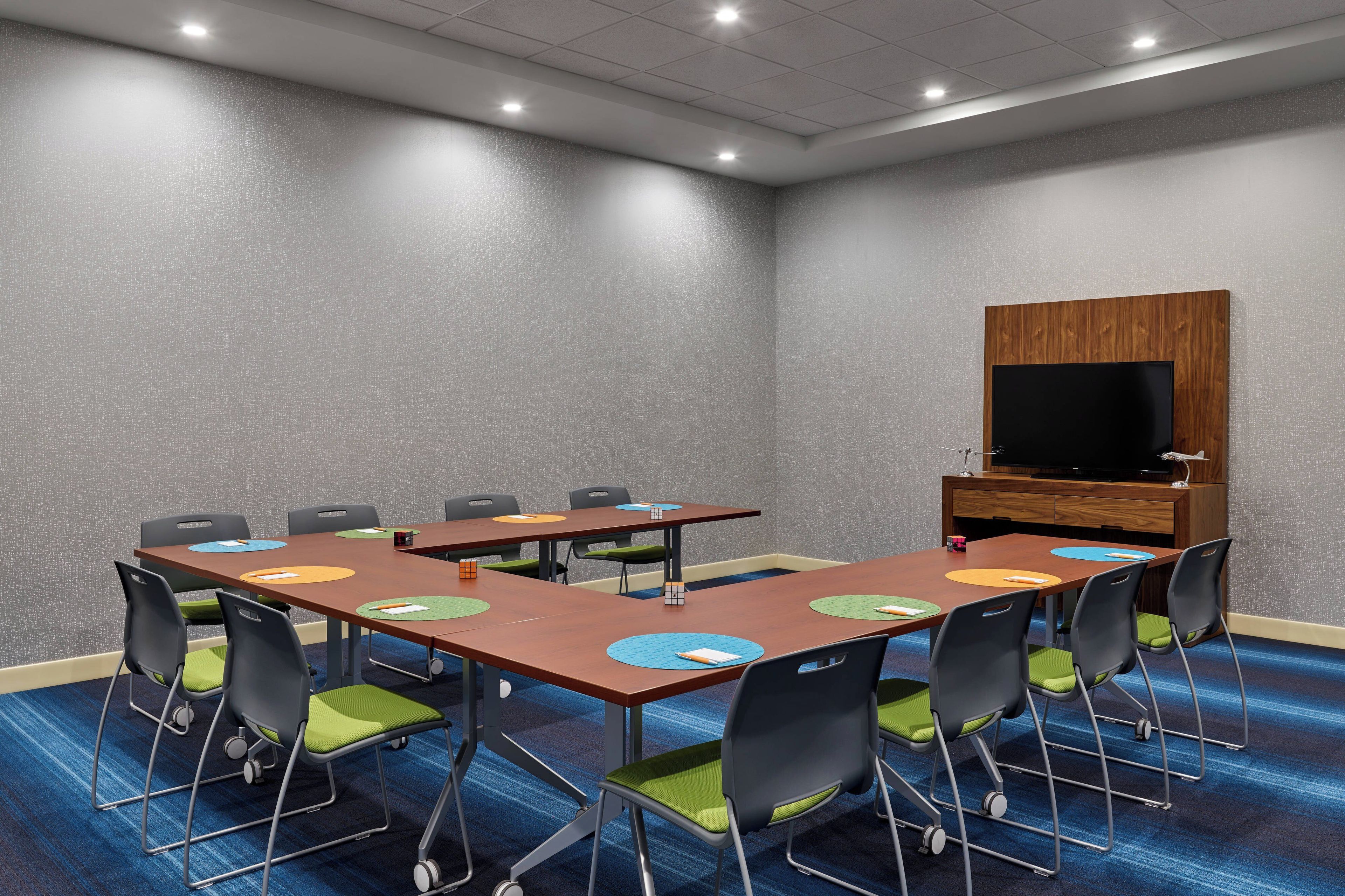 A conference room with a large table, chairs, a television, and a wooden cabinet.