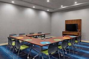 A conference room with a large table, chairs, a television, and a wooden cabinet. - Aloft by Marriott Houston Downtown (Houston)