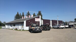 A motel with a signboard, a parked truck, and several other vehicles in the parking lot. - Jubilee Motor Inn (Davidson)