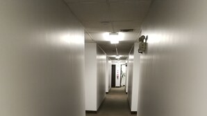 A long, narrow hallway with white walls and a carpeted floor, leading to an exit door at the end. - Jubilee Motor Inn (Davidson)