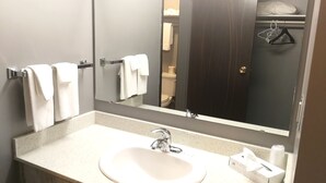 A bathroom with a white sink, a mirror, and a towel rack. - Jubilee Motor Inn (Davidson)