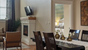 A dining area with a fireplace, a TV mounted on the wall, and a view of a bedroom through an open door.