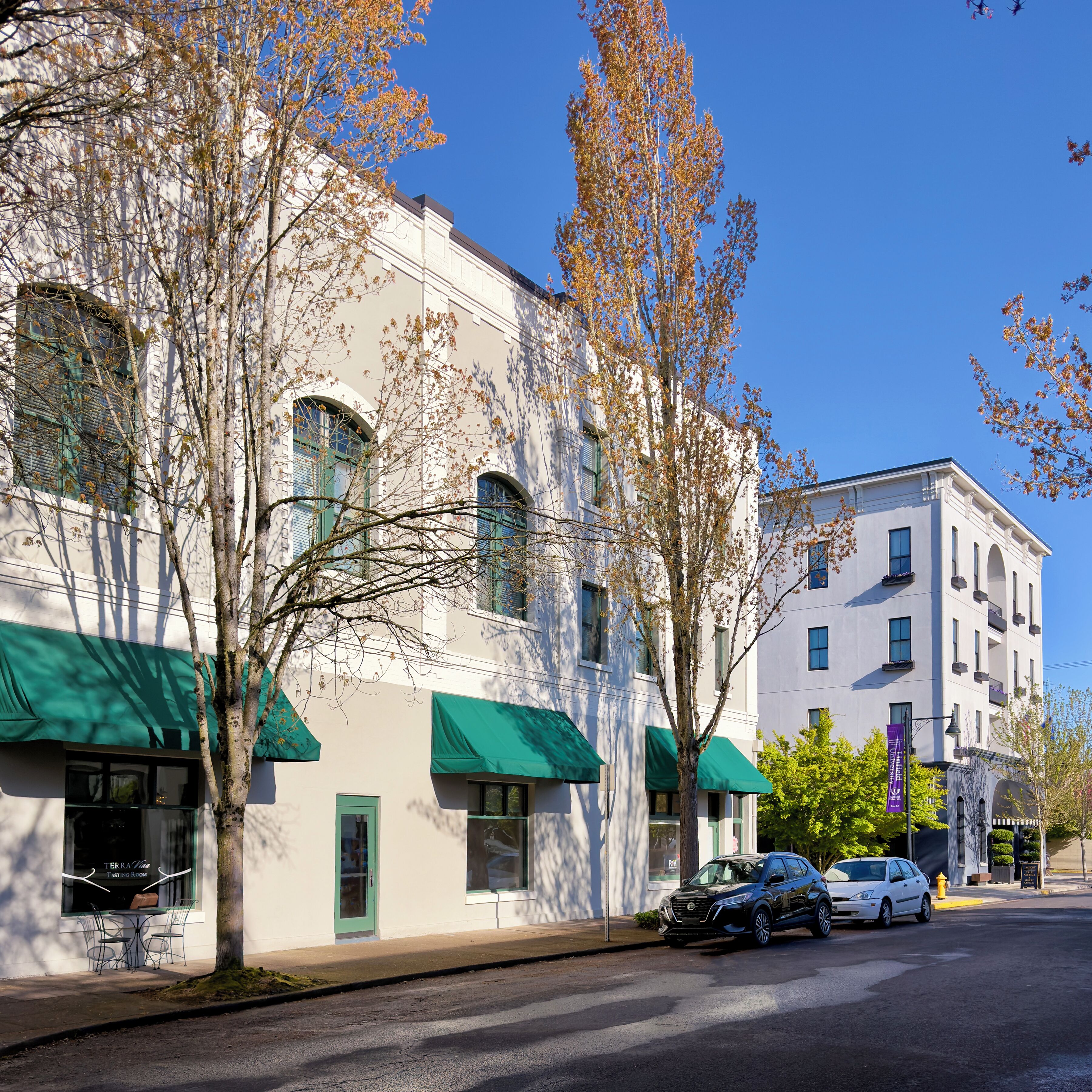 Un bâtiment avec un auvent vert, une voiture garée et un ciel bleu dégagé.