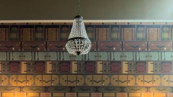 A neatly made bed with pillows, a hanging chandelier, and a wall with patterned wallpaper.