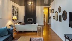 A modern living room with a fireplace, a sofa, a coffee table, and a chandelier.