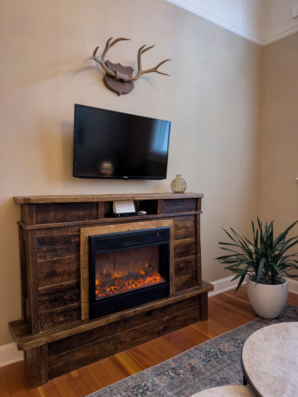 A fireplace with a TV above it, a mounted deer head, and a potted plant.