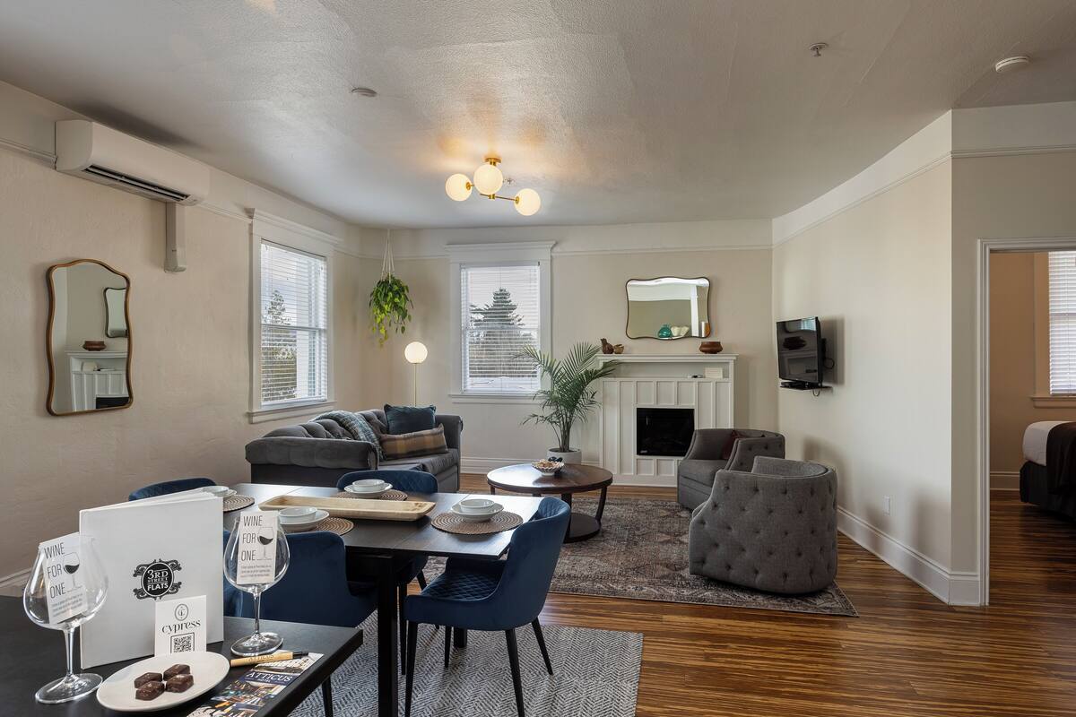 A living room with a fireplace, a dining area with a table and chairs, and a seating area with a sofa and ottoman.