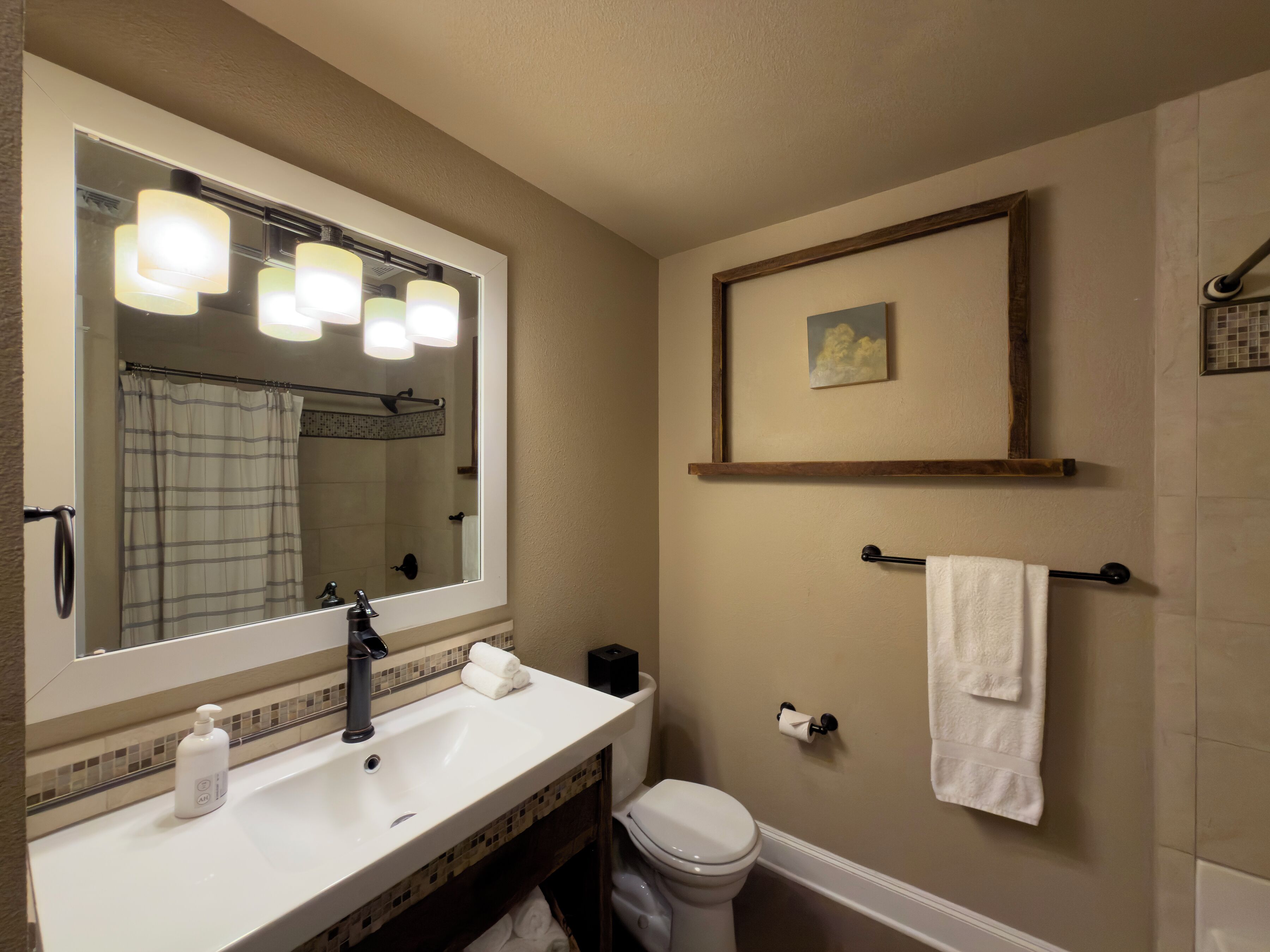 A bathroom with a large mirror, a sink, a toilet, and a towel rack.