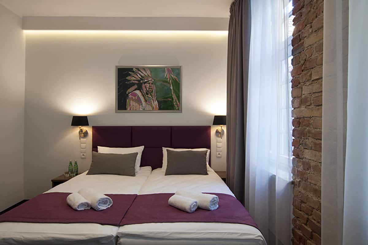 A double bed with two pillows, a headboard, and a painting above it.