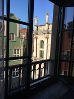 Vista dalla finestra con balcone, su un edificio con architettura classica e statue.