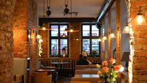 A cozy restaurant with brick walls, wooden tables, and hanging lights. - Liberum Residence (Gdansk)