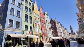 A bustling square with colorful historic buildings, a café, and people walking.