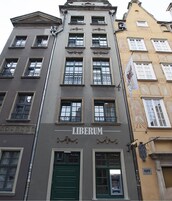 A building with the sign "LIBERUM" on the facade, featuring multiple windows and a green door.