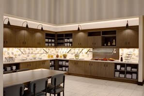 Una cocina moderna con armarios de madera, una mesa de comedor y sillas. Hay luces colgantes y un salpicadero con diseño.