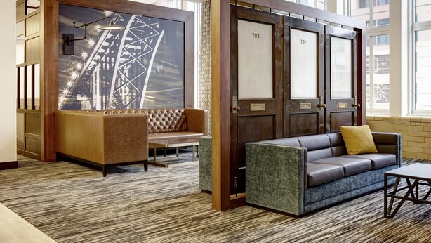A modern lobby with a sofa, a bench, and a couch. There are two doors with numbers 703 and 702.