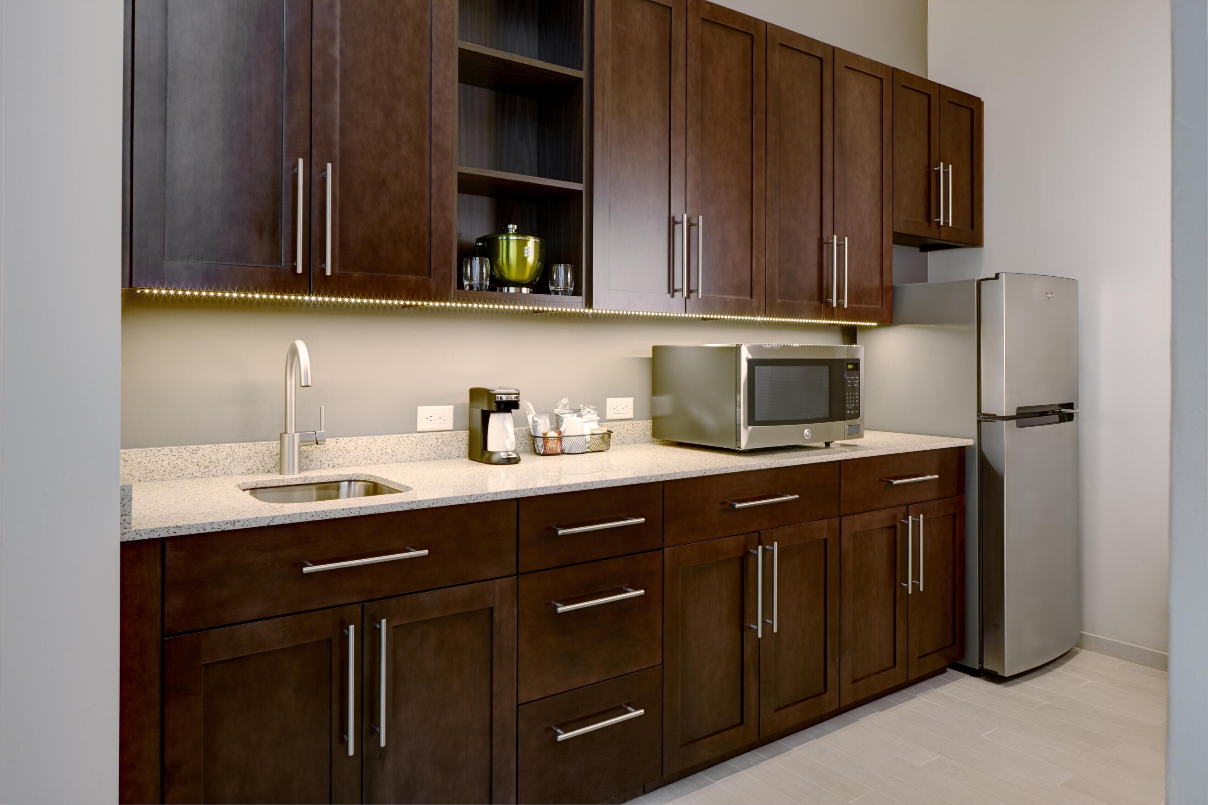 A modern kitchen with dark wooden cabinets, stainless steel appliances, and a granite countertop.