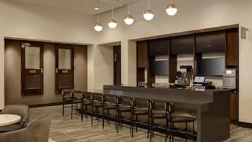 A hotel lobby with a reception desk, seating area, and a minibar.