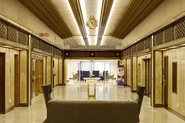 A spacious lobby with a central seating area, a clock on the ceiling, and patterned wall designs.