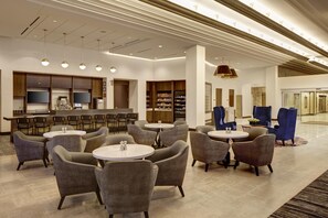 A modern hotel lobby with a bar area, seating arrangements, and a reception desk.