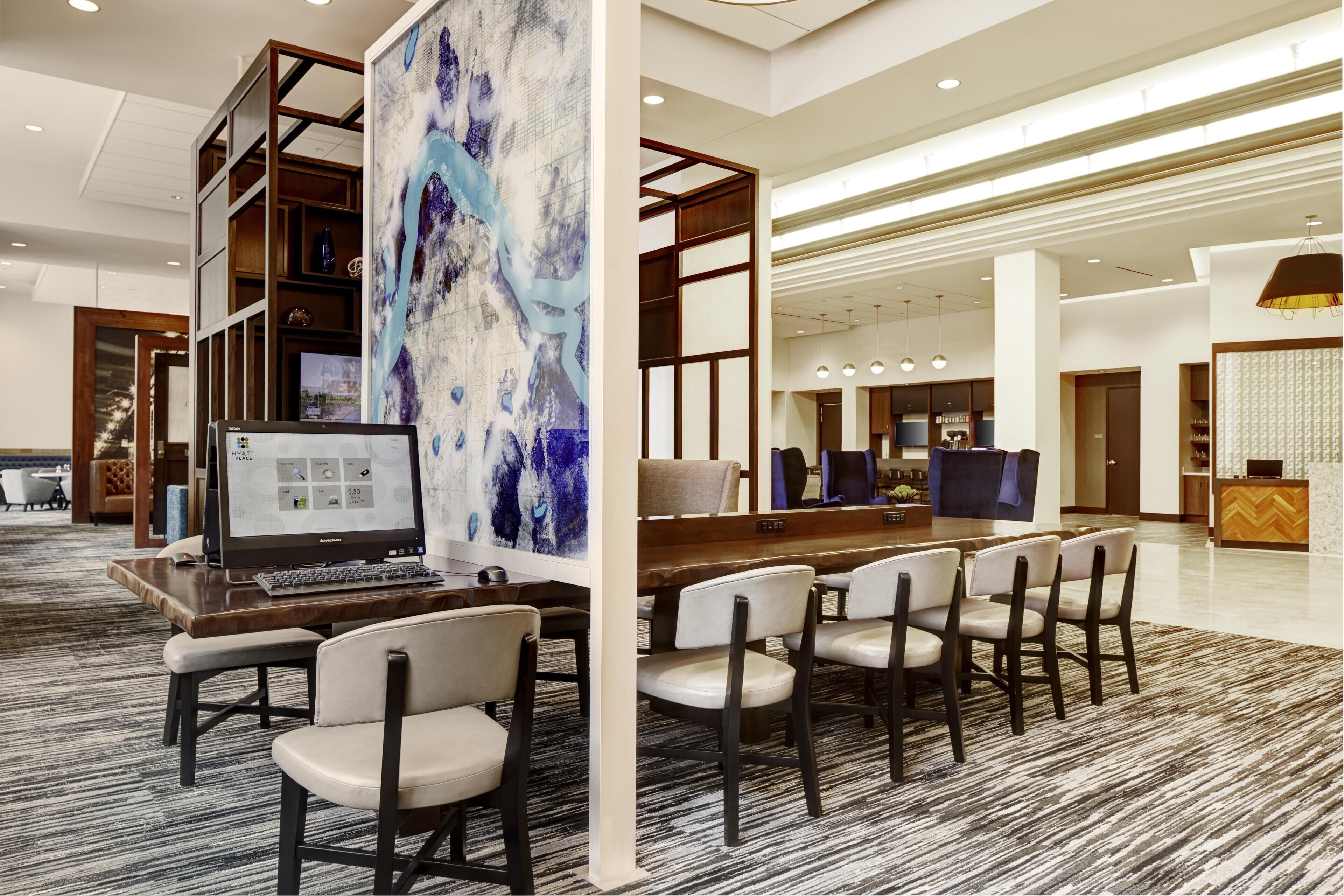 Un hall de hotel con mostrador de recepción, zona de estar y un cuadro abstracto de gran tamaño.