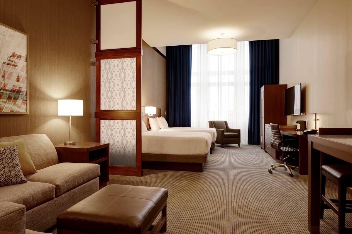 Een hotelkamer met een bed, een bureau, een stoel, een bank en een televisie.