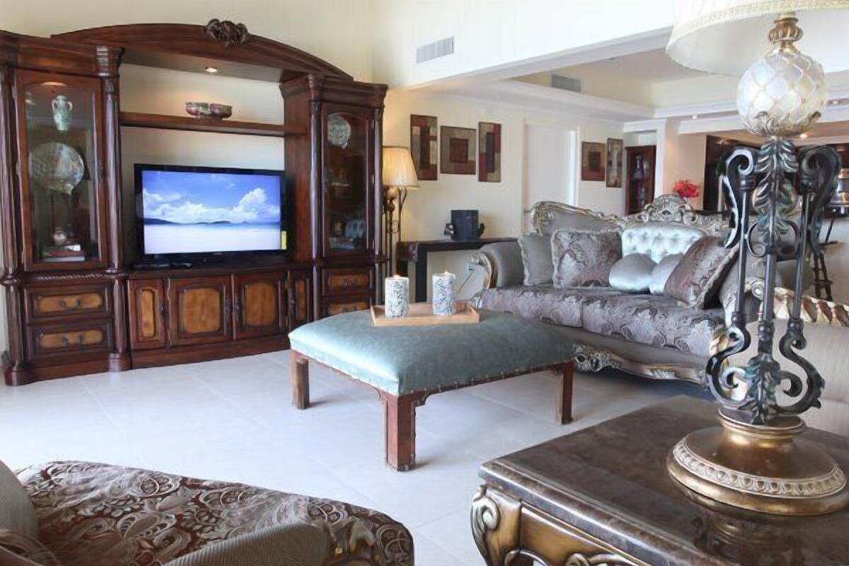 A living room with a television, ornate furniture, and a decorative lamp.