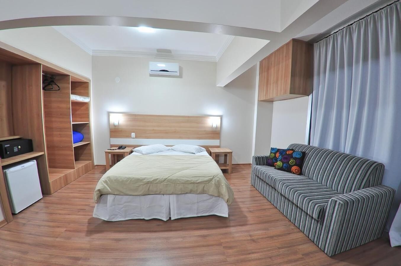 Una habitación de hotel con cama, un escritorio pequeño, un sofá y un mini refrigerador.