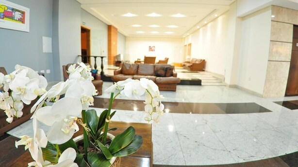A spacious lobby with a marble floor, a seating area with sofas, and white orchids in the foreground. - Turis Hotel (Passo Fundo)