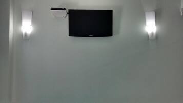 En platt-TV som är monterad på en enkel vägg, med två väggmonterade lampor på vardera sidan.