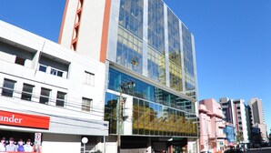 A modern building with a glass facade, a prominent sign for 'Turis', and a visible entrance. - Turis Hotel (Passo Fundo)