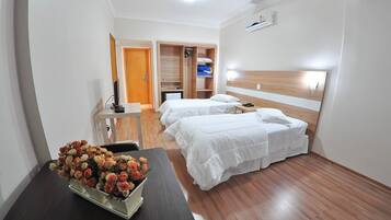 Une chambre d’hôtel avec deux lits, un bureau, une chaise, une table ornée d’un vase de fleurs et une armoire.