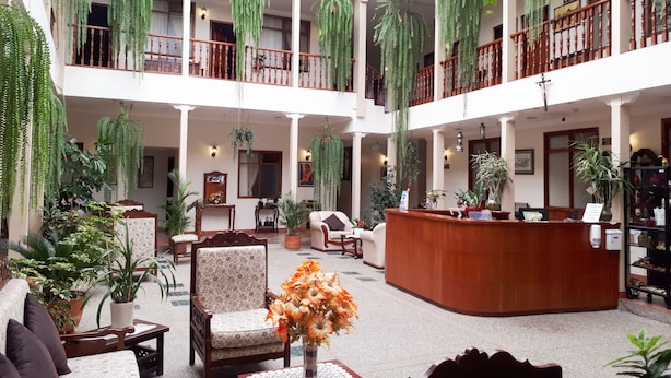 A spacious hotel lobby with multiple levels, wooden railings, and hanging plants. - Hotel Casa Montero (Quito)