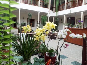 A spacious indoor atrium with multiple levels, featuring potted plants, a reception desk, and seating areas. - Hotel Casa Montero (Quito)