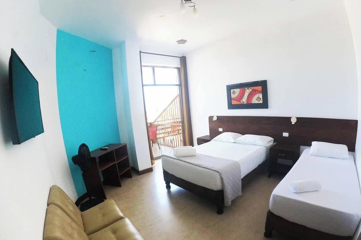 A hotel room with a bed, a desk, a chair, and a TV.