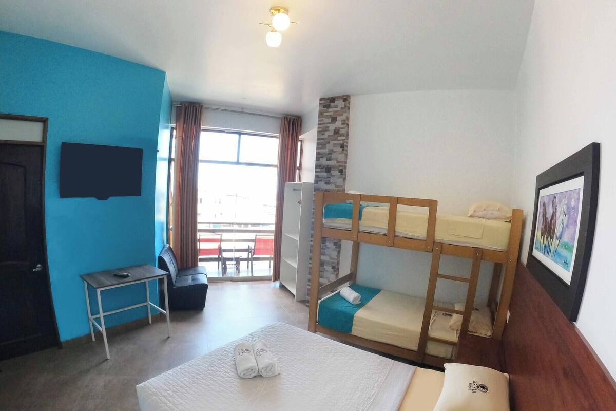 A room with bunk beds, a desk, a chair, and a bed with towels.