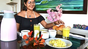 A breakfast table with various food items, a coffee maker, and a painting in the background. - Hotel Aryia (Máncora)