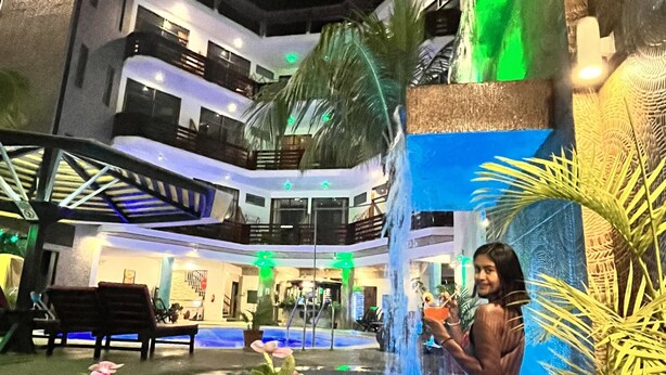 A multi-level hotel with a central courtyard featuring a water fountain, benches, and potted plants. - Hotel Aryia (Máncora)